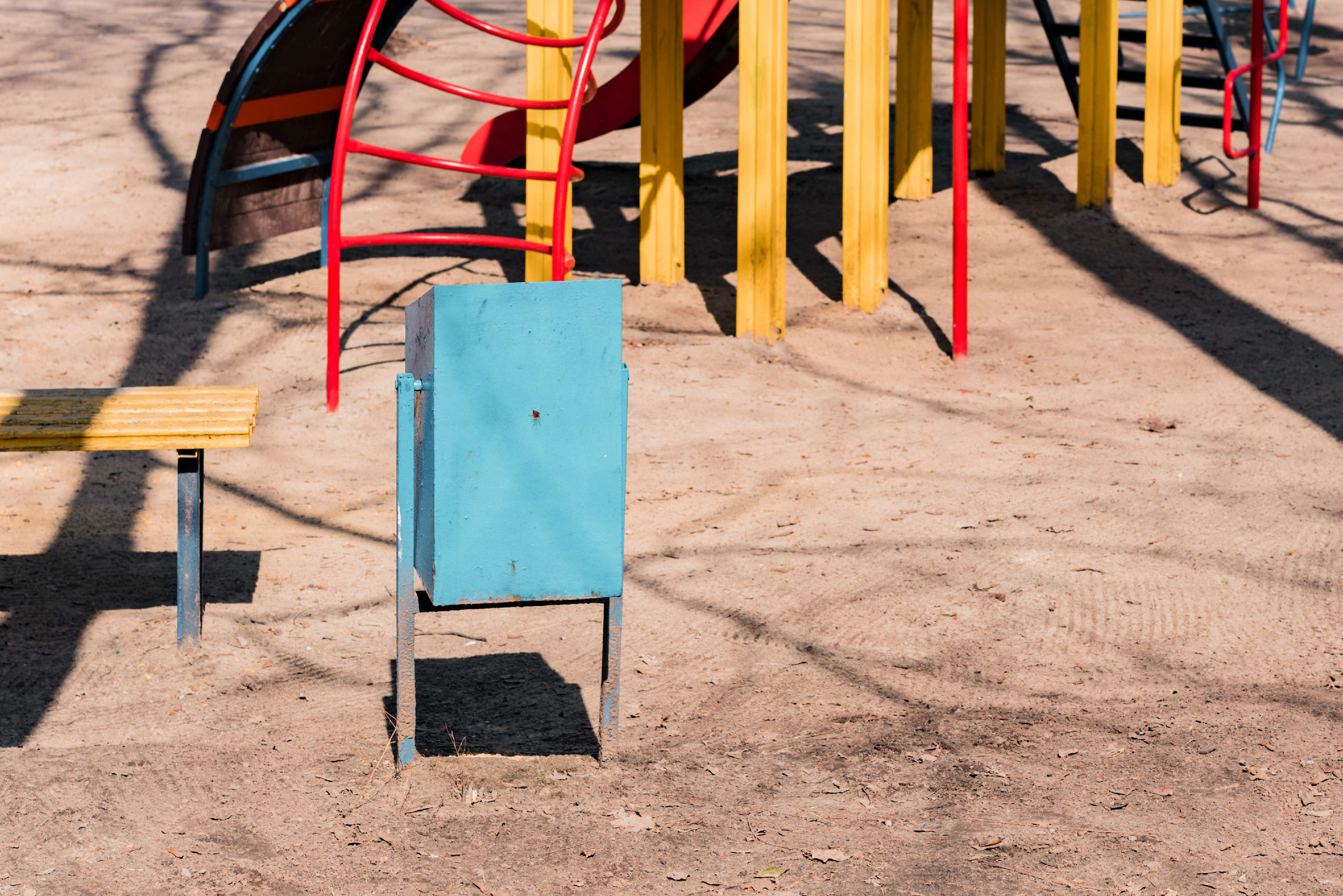 Bunter Mülleimer auf einem Spielplatz.